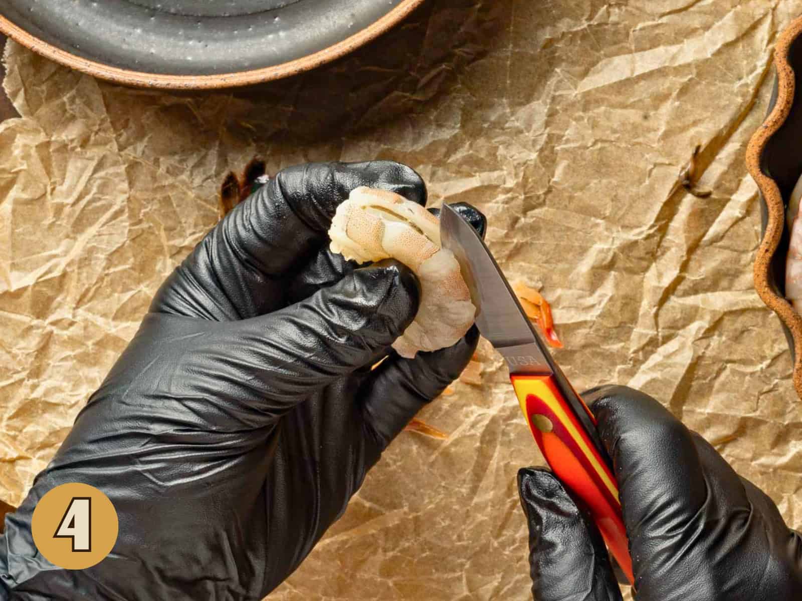 Cutting the back of a shrimp to remove the evin.