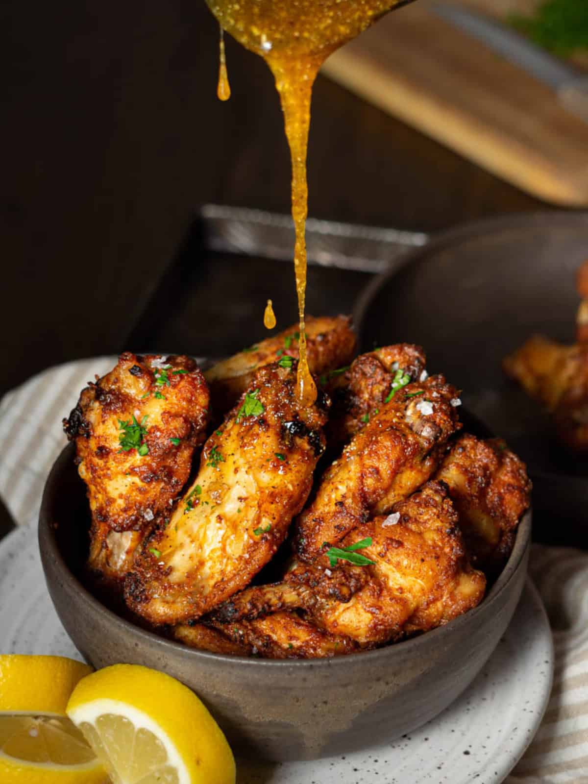 Pouring honey lemon pepper sauce on crispy wings.