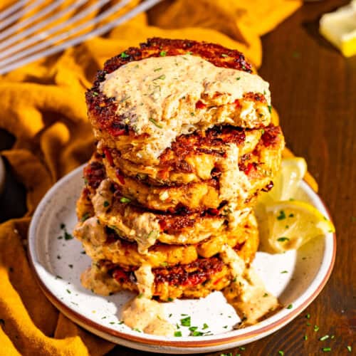 A stack of Louisiana crab cakes with a drizzle of remoulade sauce.