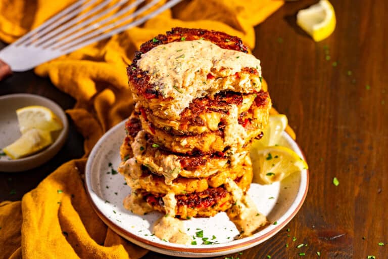 A stack of Louisiana crab cakes with a drizzle of remoulade sauce.