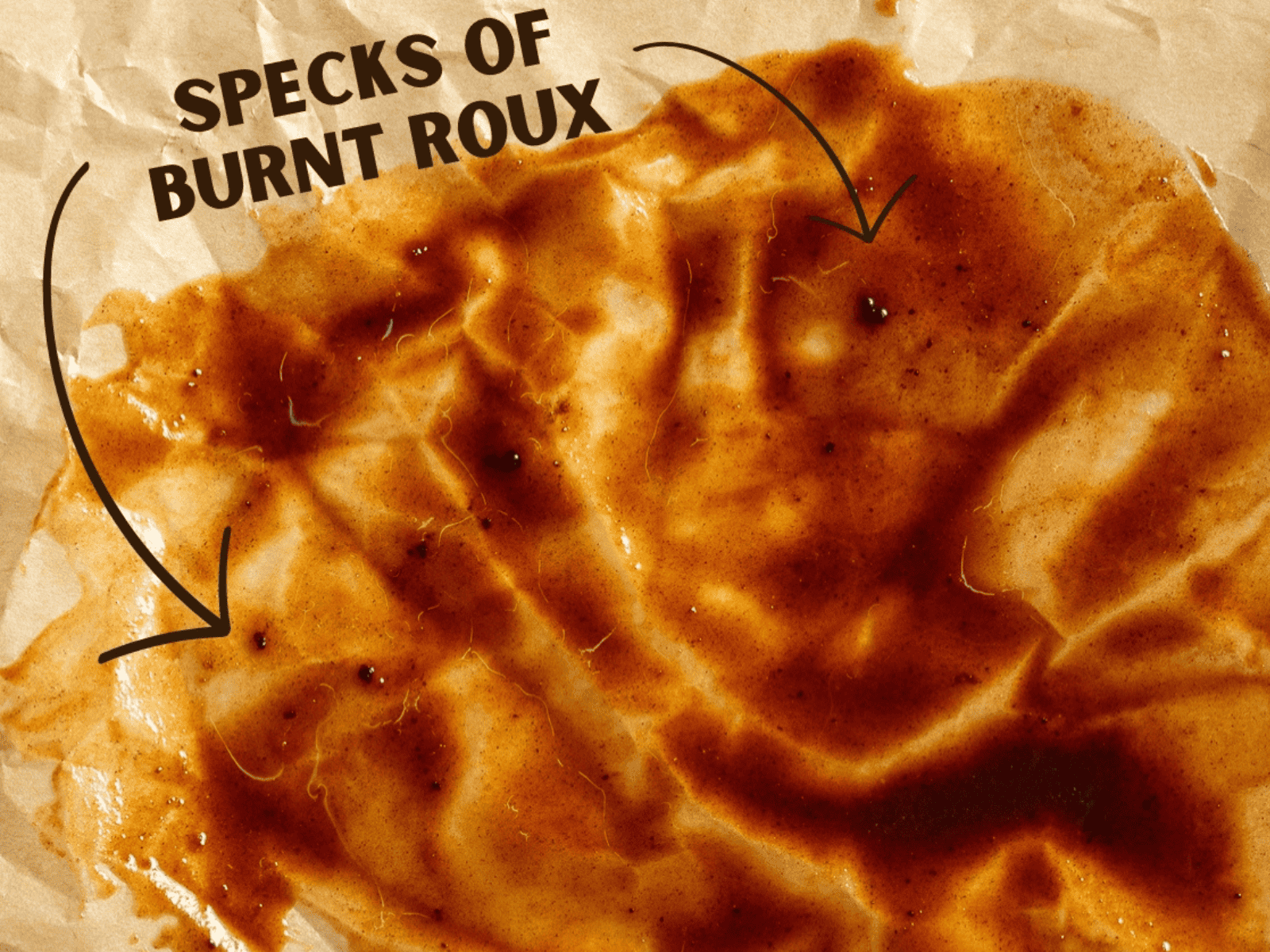 Black specks in burnt roux spread on parchment paper.
