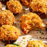 Crab stuffed mushrooms on a tray and one with a bite taken out.