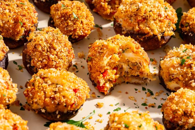 Crab stuffed mushrooms on a tray and one with a bite taken out.