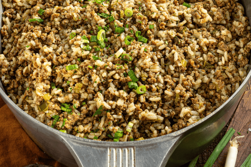 Louisiana dirty rice in a pot with green onions.