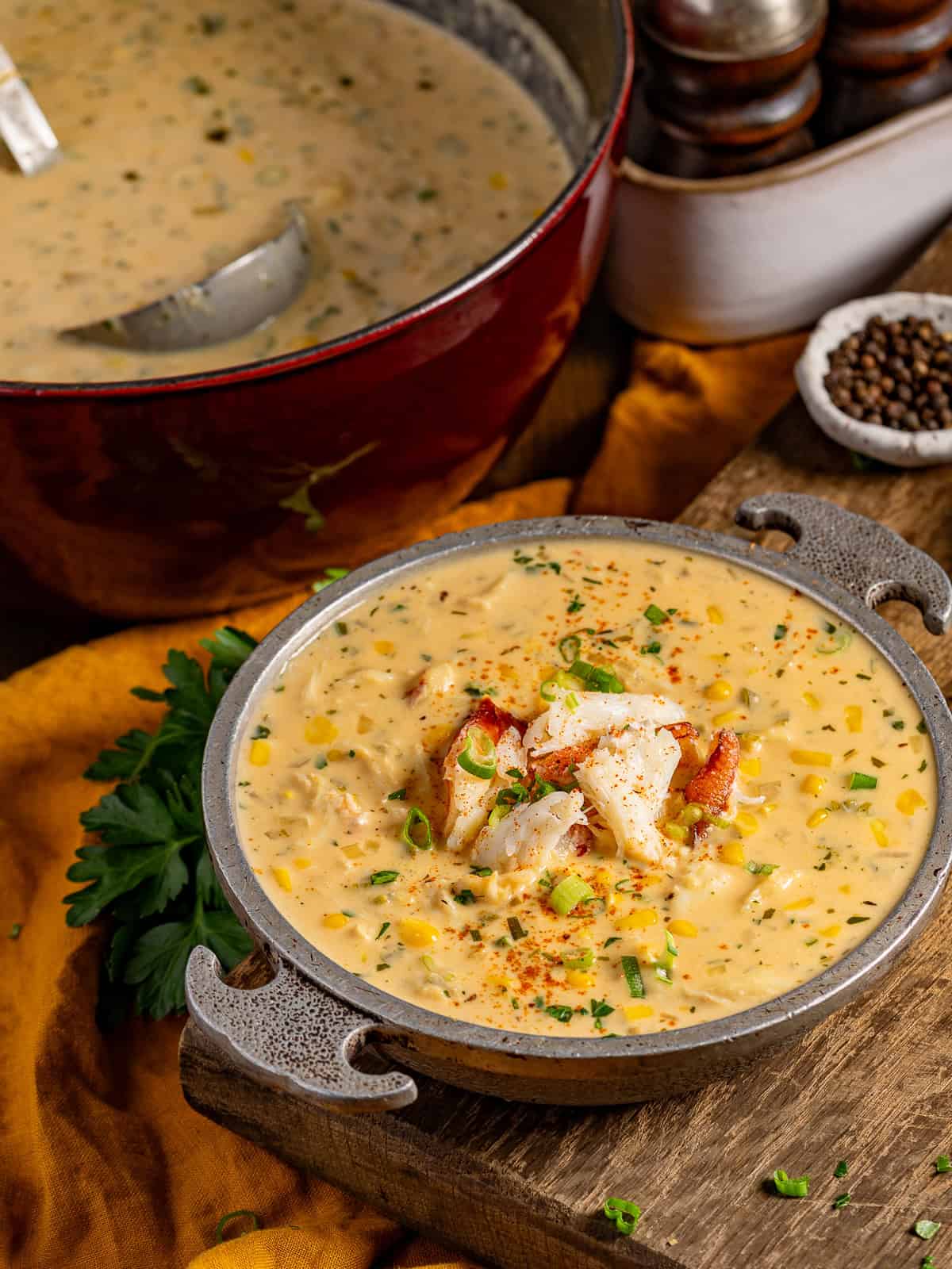 A pot of creamy corn and crab bisque with a bowl served.