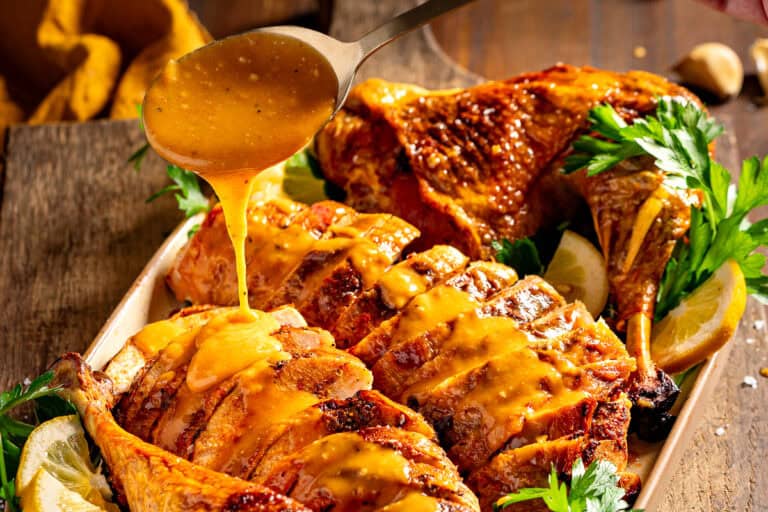 Drizzling cajun gravy onto sliced turkey.