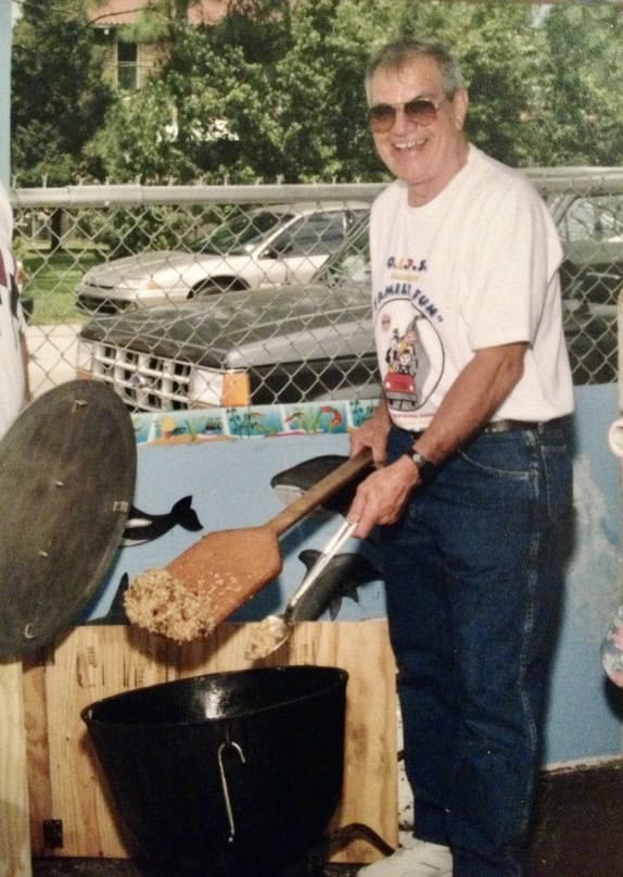 A man stirring a big jambalaya pot.