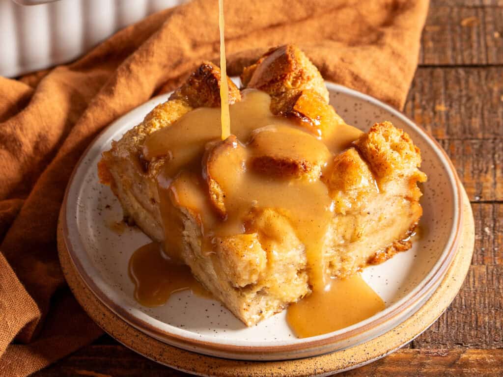 Drizzling bourbon sauce on a slice of bread pudding.